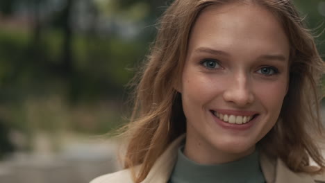 caucasian woman looking at the camera and smiling outdoors.