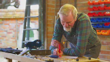 senior male carpenter in garage workshop sketching out design on paper