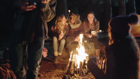 Amigos-Sentados-Junto-A-Una-Fogata-Joven-Tocando-Ukelele-Cantando-A-Una-Mujer-Disfrutando-De-Una-Serenata-Romántica-Acampando-En-El-Bosque-Por-La-Noche