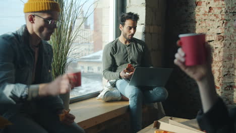 friends enjoying pizza lunch by the window