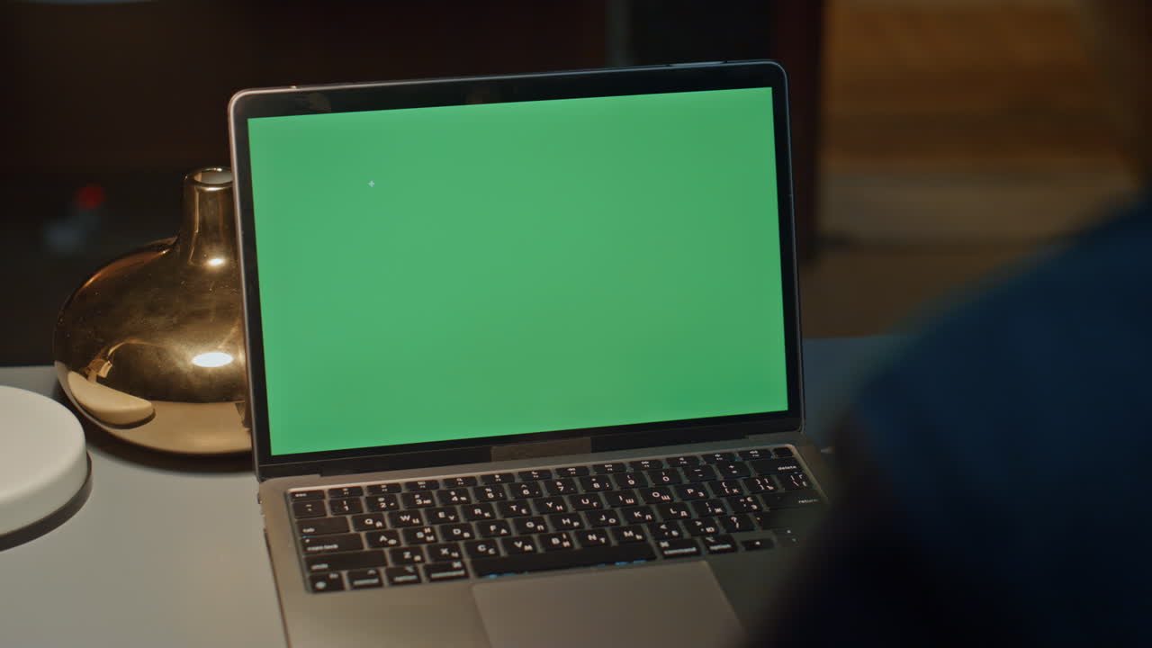 Man hands typing greenscreen laptop at evening home workplace closeup. Late work