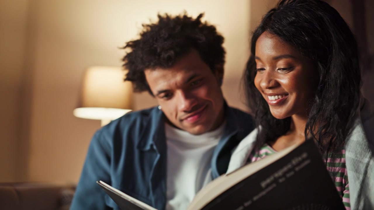 Carefree lovers holding book relaxing in modern apartment closeup. Happy people