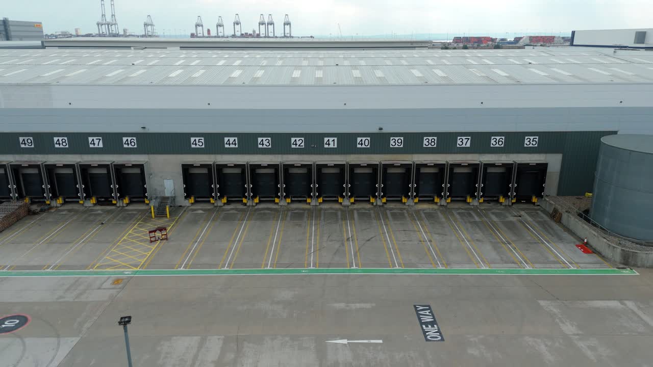 Ripresa aerea con drone di magazzini industriali e centri di distribuzione nel porto di Londra sul Tamigi che mostra l'infrastruttura logistica e il commercio globale