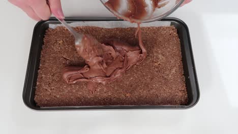 spreading chocolate icing on a slice