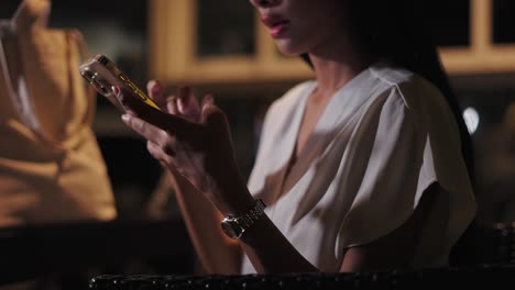 Woman using smartphone at night in a restaurant