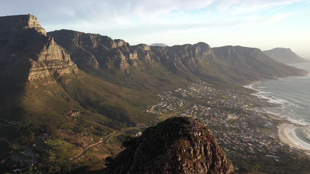 dramática toma aérea cinematográfica que revela el pico de la cabeza de león de ciudad del cabo con la montaña de la mesa, la bahía de campamentos y clifton durante la puesta de sol de la hora dorada