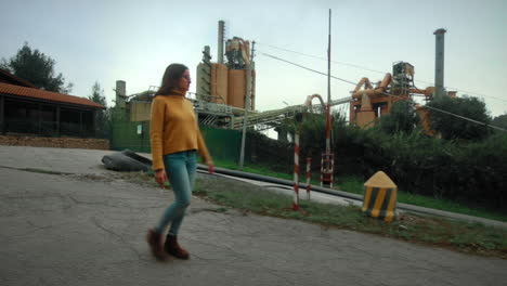 young girl roaming around a factory in a cloudy day