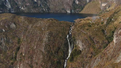 4k daytime video with a high waterfall stream being revealed in the peruvian andes - 5 lakes (lagoons) of pichgacocha, ambo, huanuco. boom-jib down, wide angle shot.