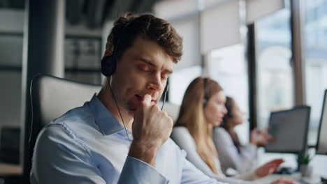 Thoughtful-support-agent-listening-customer-at-workplace.-Focused-man-specialist