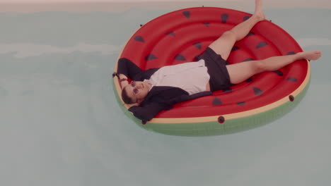 man relaxing in pool on watermelon float