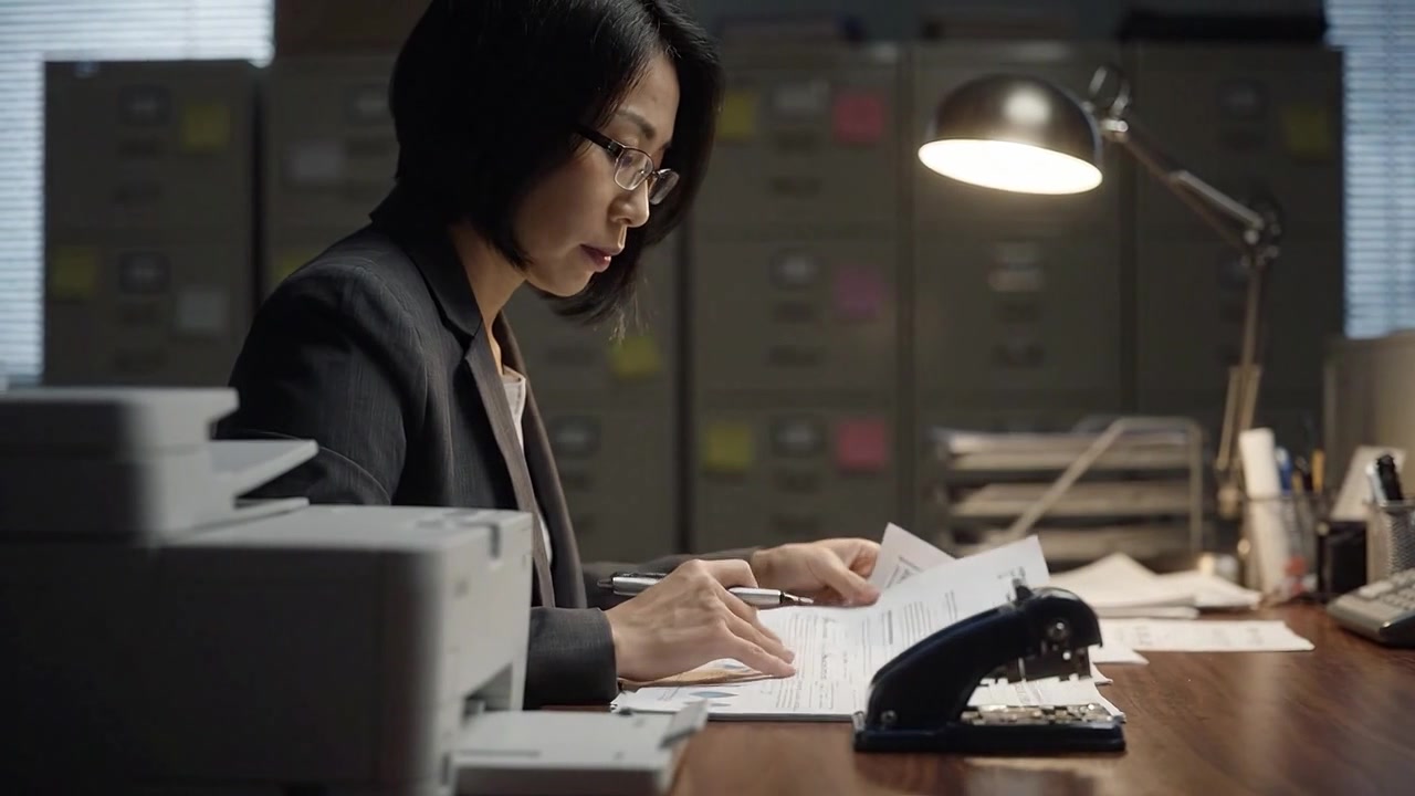オフィス環境でレポートとデータを分析し、書類作成を行いながらクリティカルシンキングと組織力を発揮する集中したプロフェッショナル。