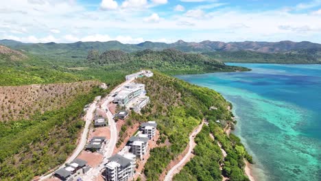 coastal hillside resort under development in busuanga, palawan, philippines, surrounded by lush greenery and turquoise waters. aerial pullback shot