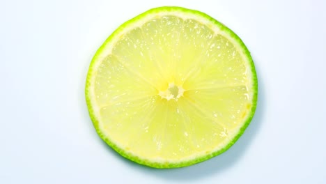 una rebanada de limón verde está girando lentamente en el estudio con los detalles.