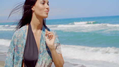 mujer sonriente pensativa caminando por la playa