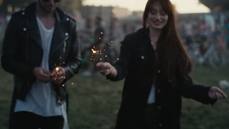 group of caucasian young people dancing on music festival with sparklers.