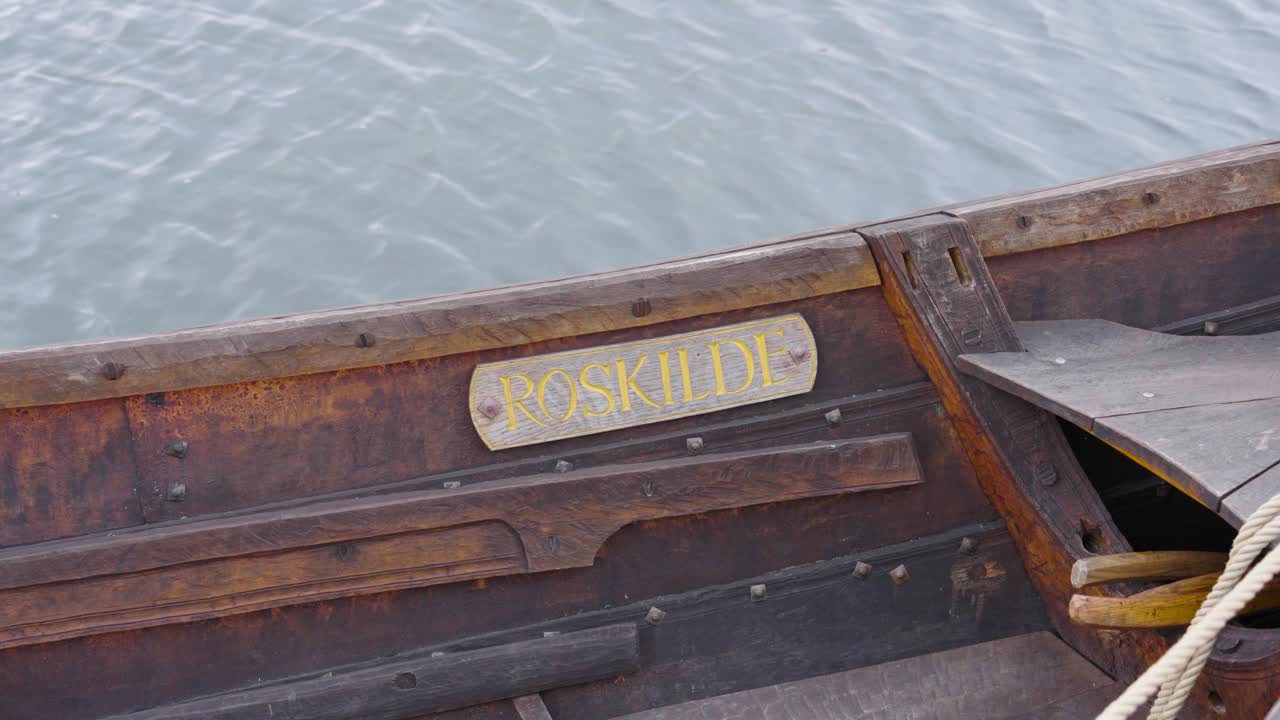 Name tag attached on vintage wooden boat floating on water, Denmark