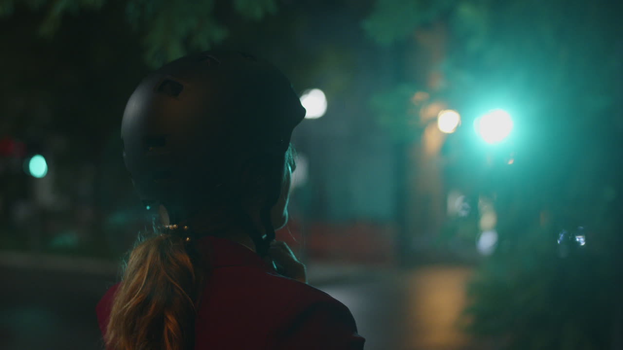 Young lady wearing a bike helmet in front of a city traffic light