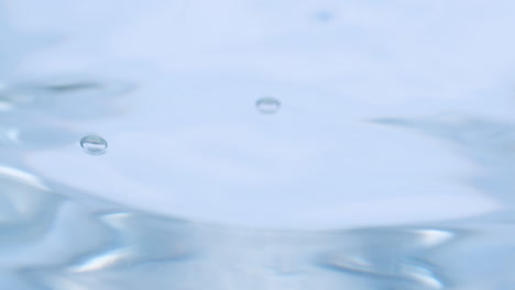 a close-up of the droplets of water that created a ripple and waves in a glass of crystal clear water