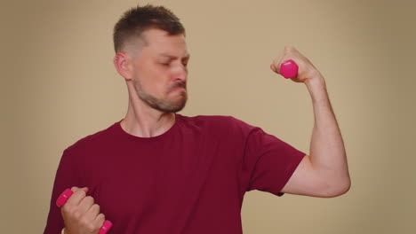 man working out, pumping up arm muscles lifting pink dumbbells, practicing pilates, healthcare