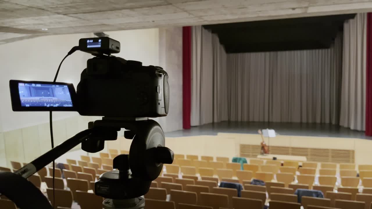 cámara en un pequeño concierto vacío de acero con muchas sillas y un escenario vacío en un trípode