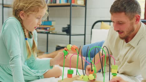 father and daughter playing with wooden puzzle toy on bed