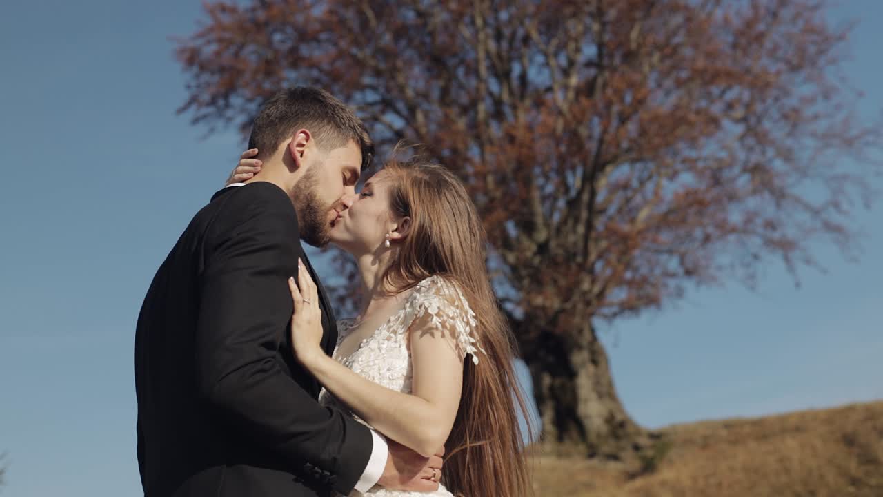 Recién casados. Novio caucásico con la novia cerca de un hermoso árbol de otoño. Pareja de boda.