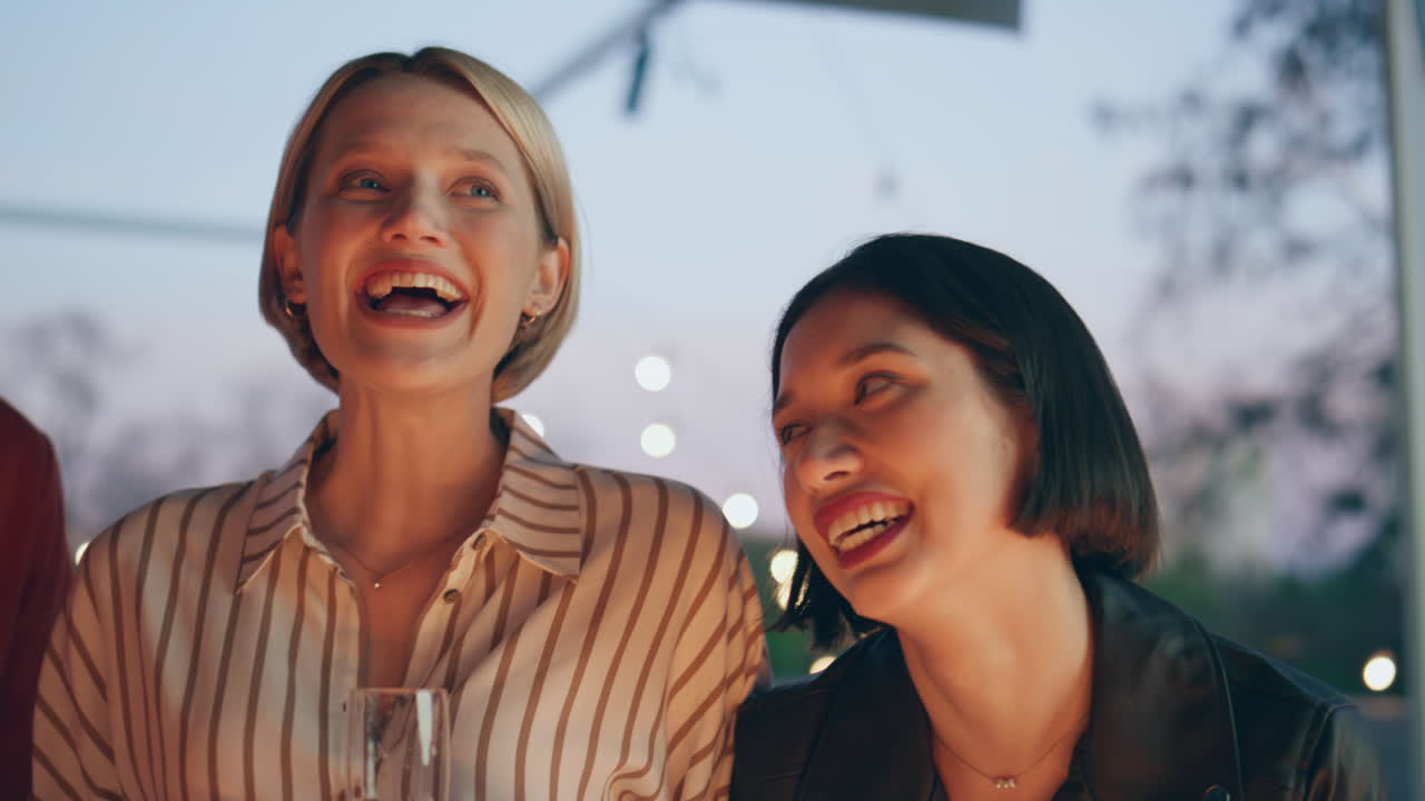 젊은 동료들이 파티 바 테라스를 즐기고 있습니다. 페인을 들고 있는 친구들