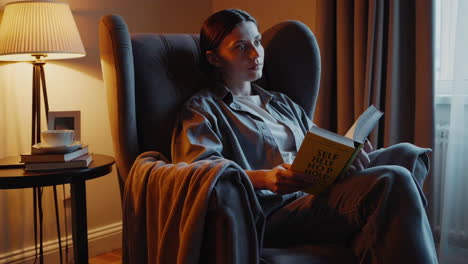 woman reading self-help book in cozy living room