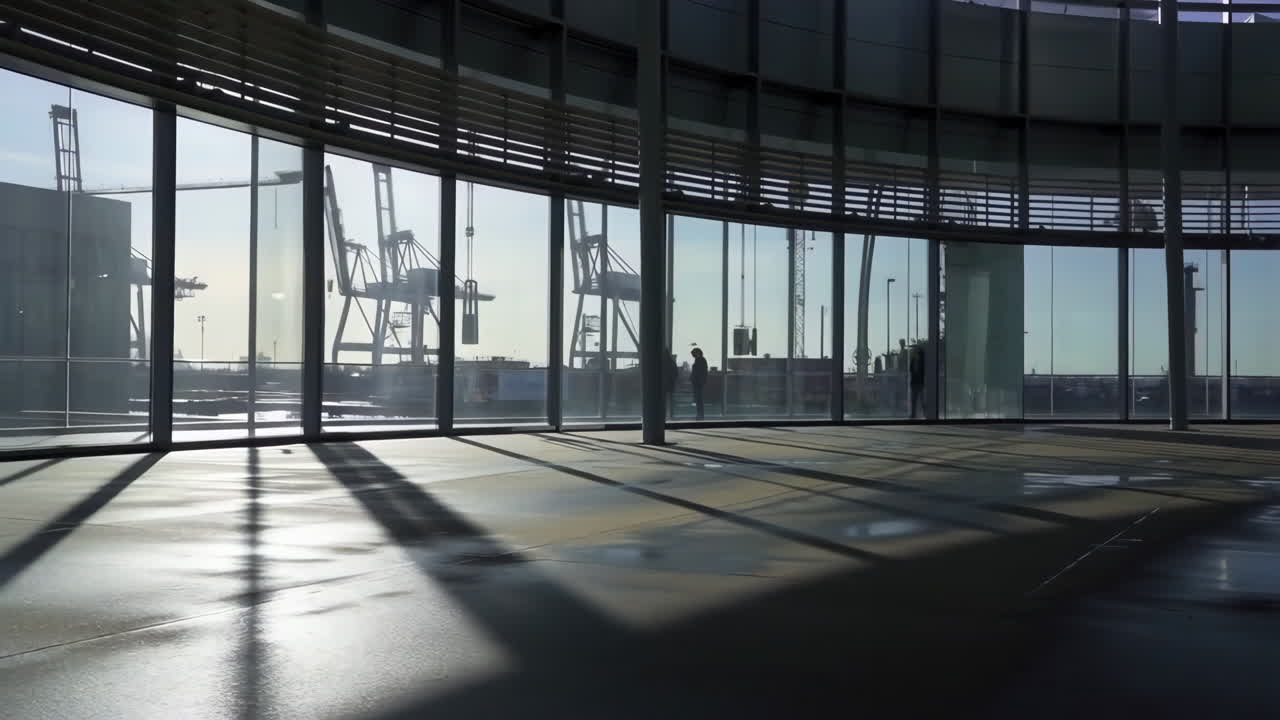 Modern building interior with curved windows overlooking a port and industrial cranes