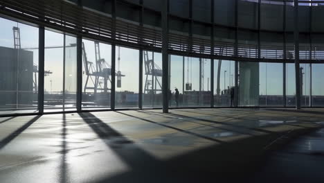 modern building interior with curved windows overlooking a port and industrial cranes