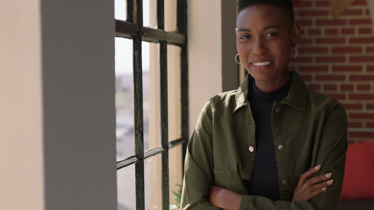 portrait beautiful african american woman looking out window smiling enjoying positive lifestyle relaxing at home trendy black female in new york apartment