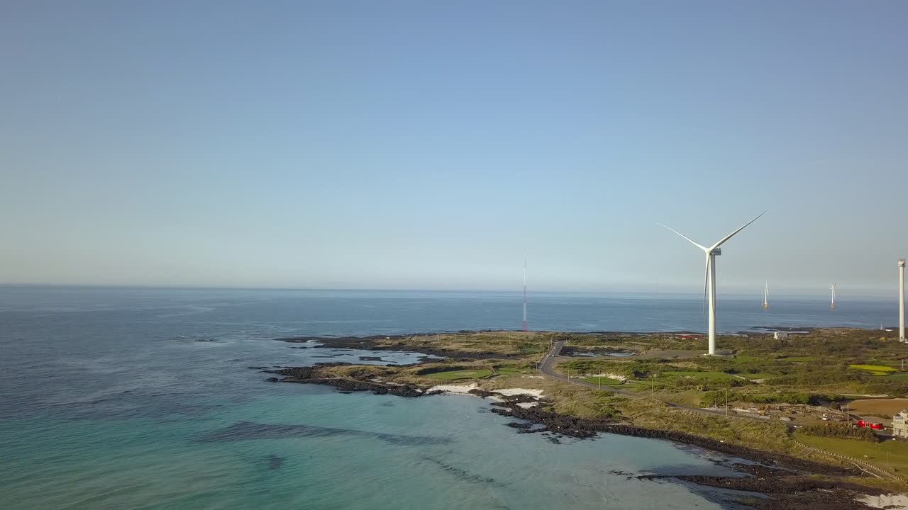 Drone flying towards wind turbine on Jeju Island, South Korea.