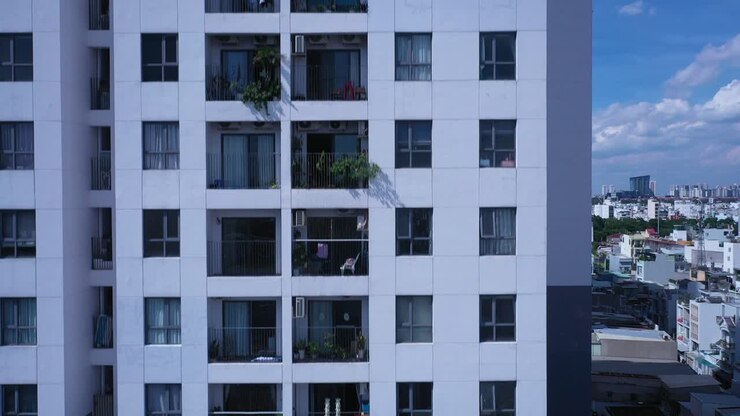 Ripresa con drone di un moderno edificio residenziale multipiano che si eleva verso l'alto in una giornata di sole, con vista su appartamenti, finestre e balconi.