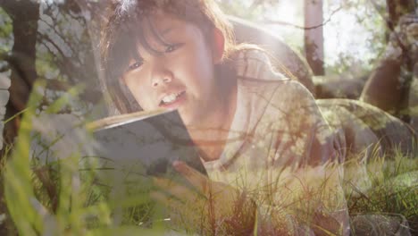 Animation-of-grass-over-happy-asian-woman-reading-book