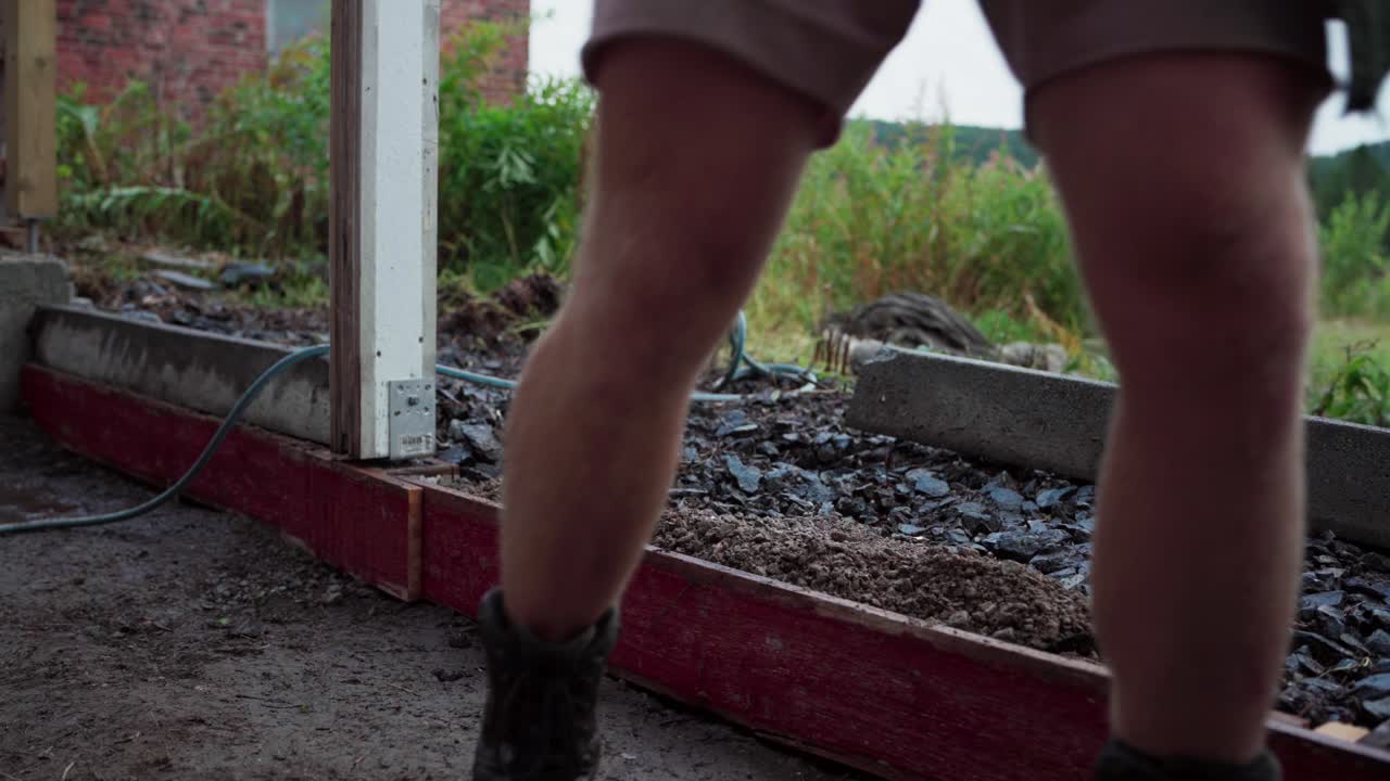 un hombre está utilizando una pala para transferir y posteriormente compactar el suelo de relleno durante la construcción de un invernadero - de cerca