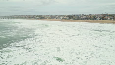 Venice-beach-of-Los-Angeles-with-foamy-ocean-in-California,-aerial-panoramic-view