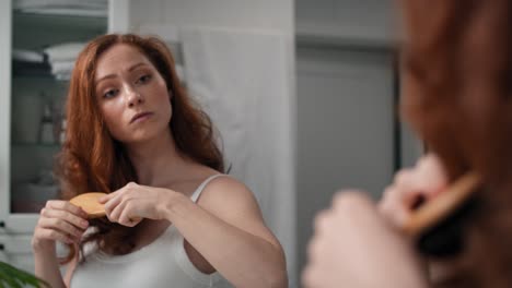 redhead woman brushing hair in the bathroom.