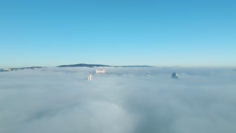 sunlit aerial journey: drone moves forward towards the bratislava castle and buildings peeking through thick inversion clouds, emphasizing the cinematic beauty of urban exploration