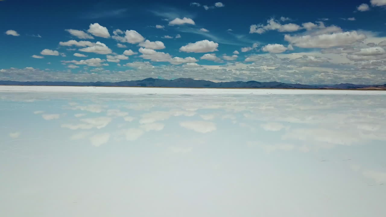 Tilt up Aerial of Majestic Salt Flat and Mirror Reflection of Blue Sky and Clouds. Salinas Grandes, Argentina
