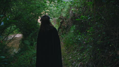 una joven druida caminando en un bosque de espaldas tiro largo