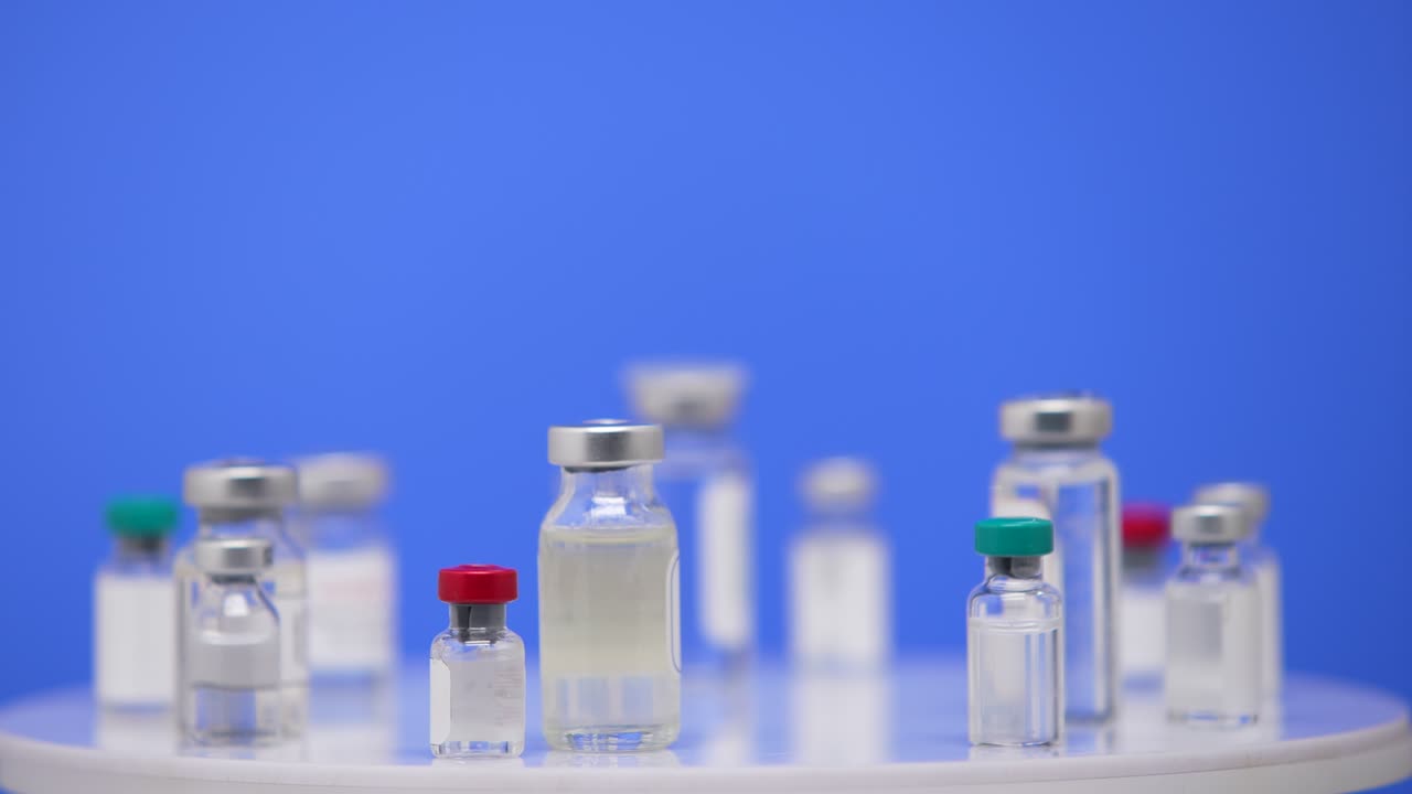 코로나19 백신은 실험실 테이블 위에 플로 어져 있습니다. 파란색 배경: 코로나바이러스 대유행에 대한 약물학적 약물, 2019-ncov에 대한 의학적 백신, 파란색 화면, 크로마 키, 어 어, 느리게.