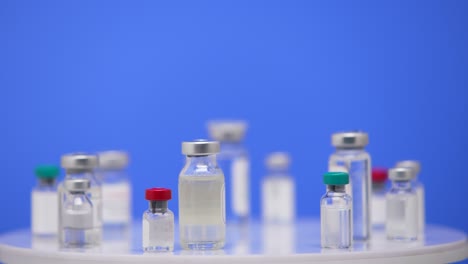 coronavirus-impfstoff in ampullen in der nähe auf einem labortisch blauer hintergrund. pharmakologische arzneimittel gegen die pandemie covid-19. medizinischer impfstoff von 2019-ncov. blauer bildschirm, chroma-schlüssel. in der nähe. langsam.