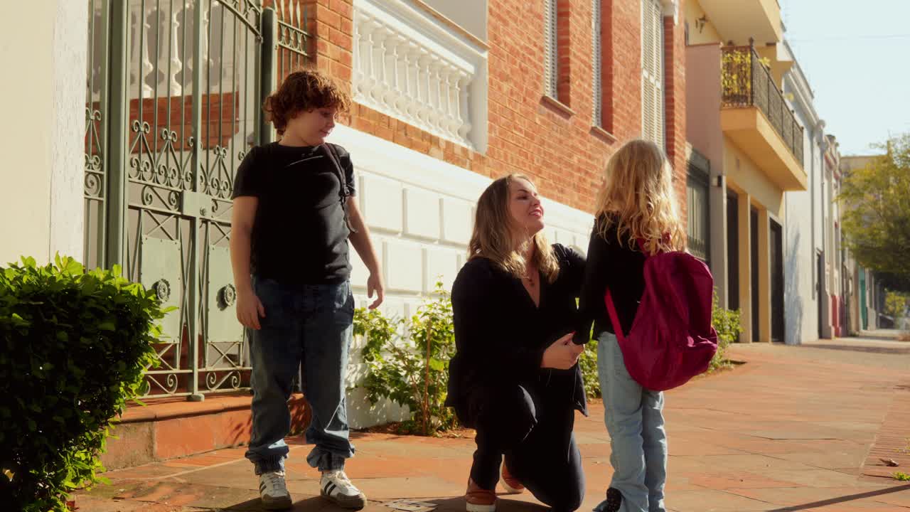 A mother shares heartfelt moments with her son and daughter on a sidewalk