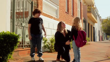 a mother shares heartfelt moments with her son and daughter on a sidewalk