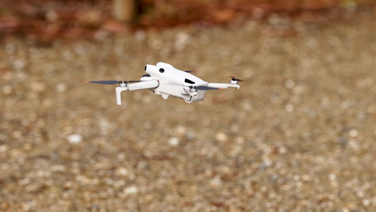 A drone descends and lands on a gravel surface in an outdoor environment with natural lighting and stable camera angles