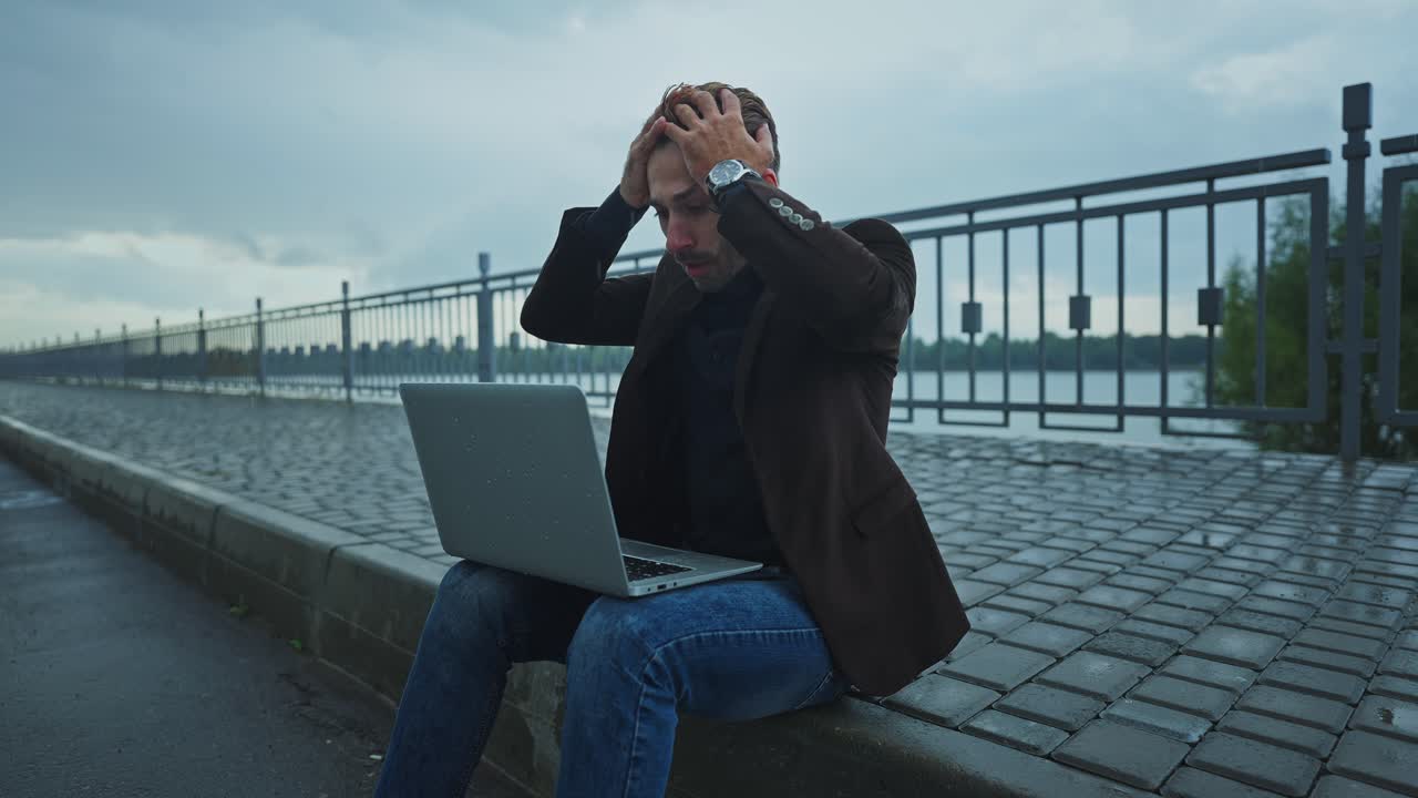 Frustrated Businessman with Laptop Outdoors in the Rain