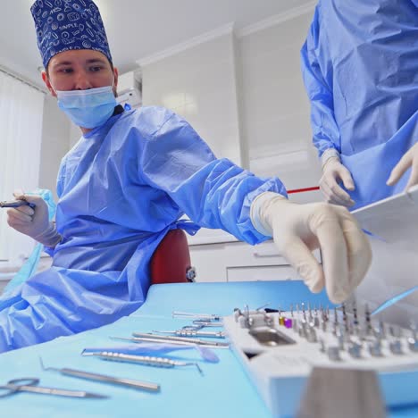 dentist is preparing tools for tooth treatment. assistant gives the doctor sterile instruments at the dental clinic. teamwork of doctors. health care concept.