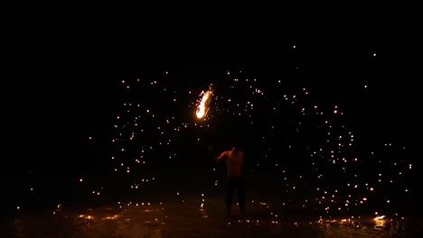 performer displays fire skills on a beach