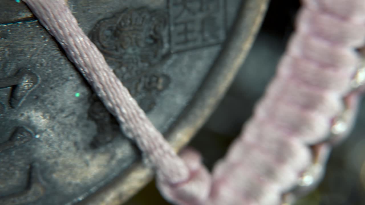 una foto macro de ensueño de una moneda de la suerte tradicional china antigua, decoración de año nuevo asiático, fondo borroso dorado brillante, agujero cuadrado, cuerdas rojas, cultura festiva, suave, lenta y crujiente pan derecha video 4k