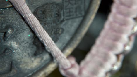 dreamy macro shot of a chinese ancient traditional lucky coin, asian new year decoration, golden shiny blur background, square hole, red strings, culture holyday, smooth slow crispy pan right 4k video